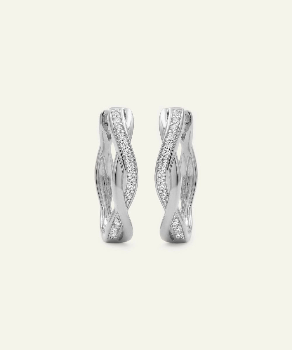 Pair of silver earrings with wavy design on a light beige background