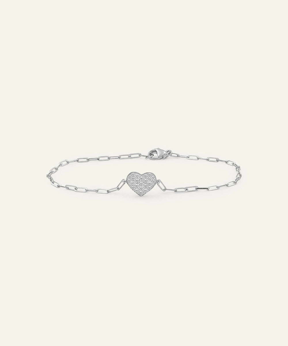 Silver bracelet with a heart-shaped charm on a light gray background