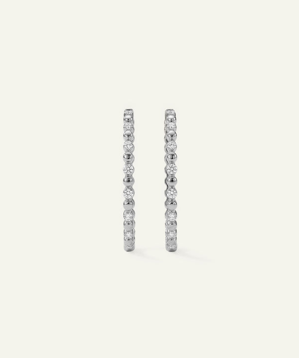 Pair of diamond hoop earrings on a light gray background