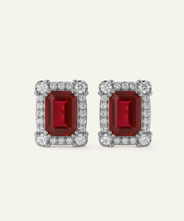 Pair of red gemstone earrings with silver accents on a white background