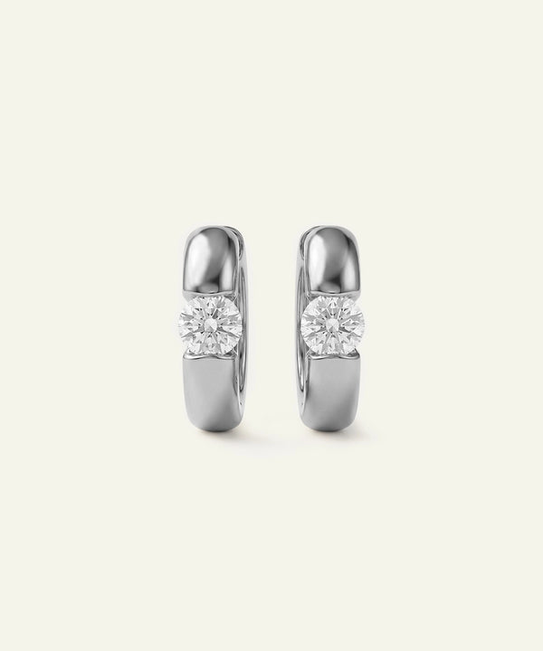 Pair of silver hoop earrings with clear gemstones on a light gray background