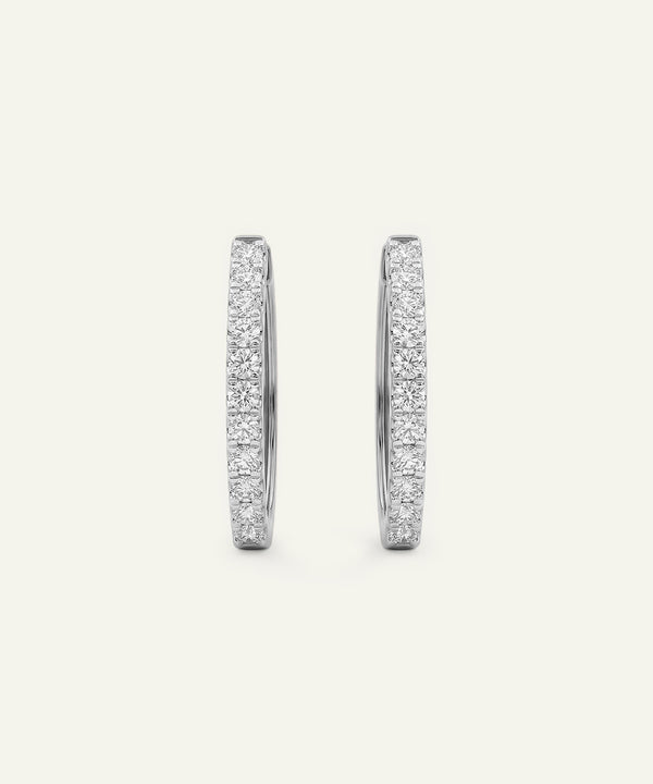 Pair of silver hoop earrings with embedded stones on a light gray background