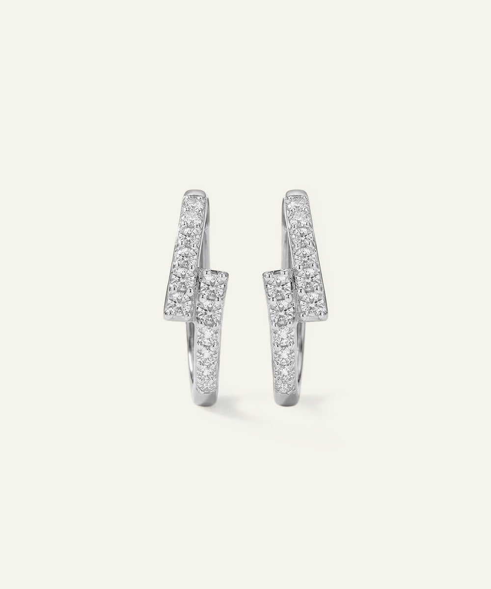 Pair of silver hoop earrings with clear gemstones on a light gray background