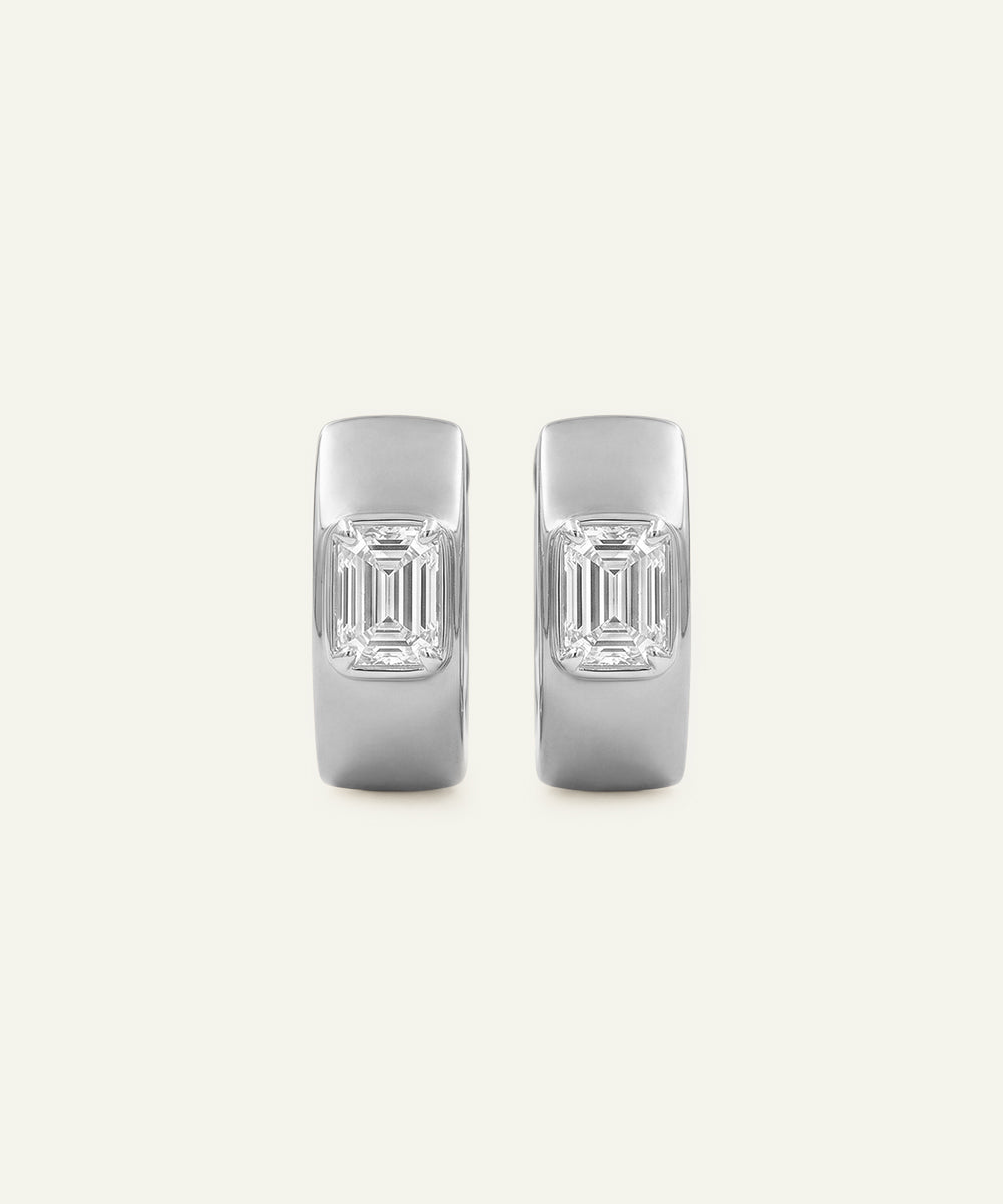 Pair of silver earrings with emerald-cut gemstones on a light gray background