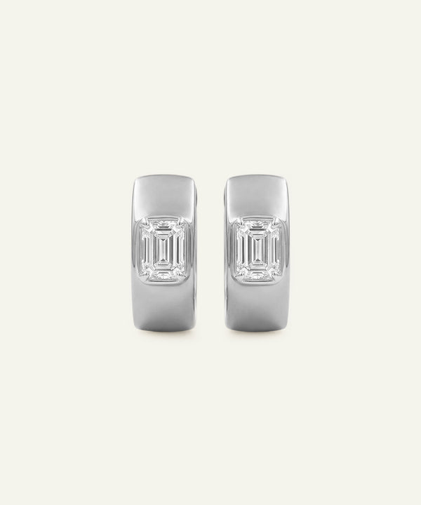 Pair of silver earrings with emerald-cut gemstones on a light gray background