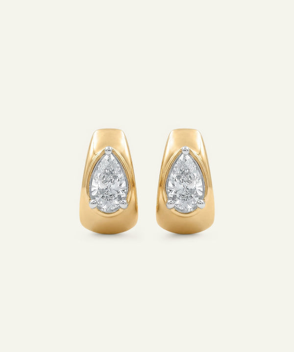 Gold earrings with pear-shaped diamond stones on a light beige background