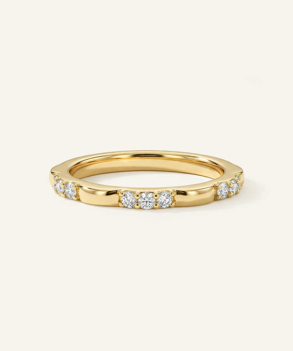 Gold ring with embedded diamonds on a light beige background