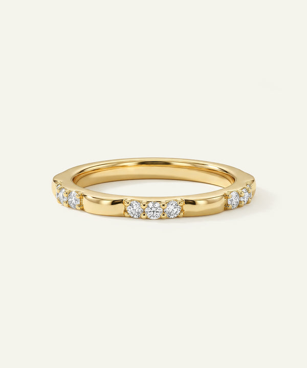 Gold ring with embedded diamonds on a light beige background