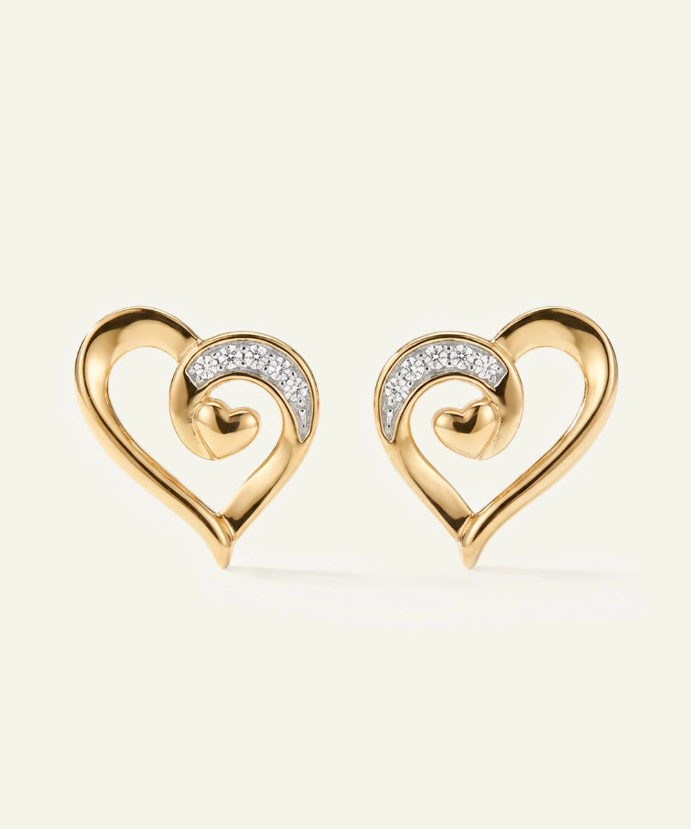 Gold heart-shaped earrings with diamond accents on a light beige background