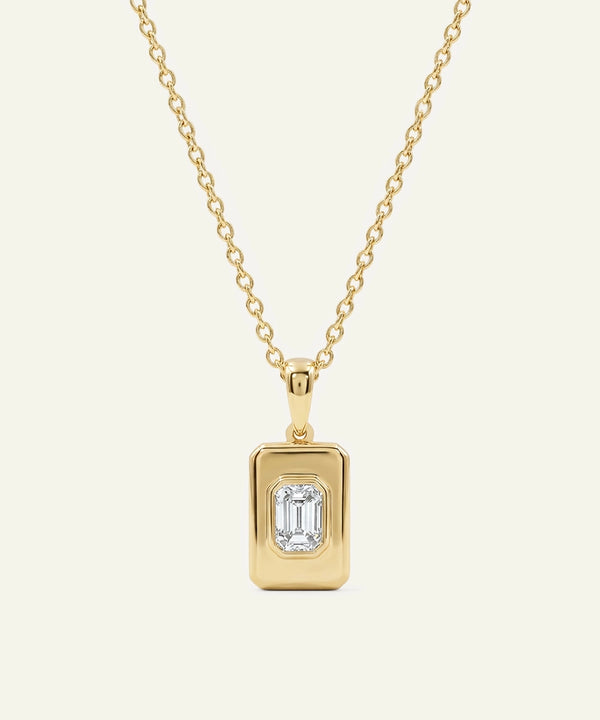 Gold necklace with a rectangular pendant on a beige background