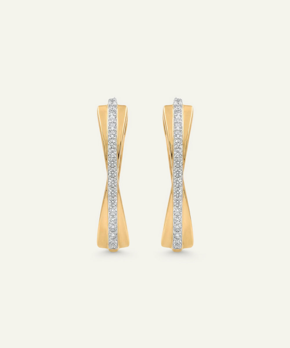 Gold earrings with diamond accents on a light beige background