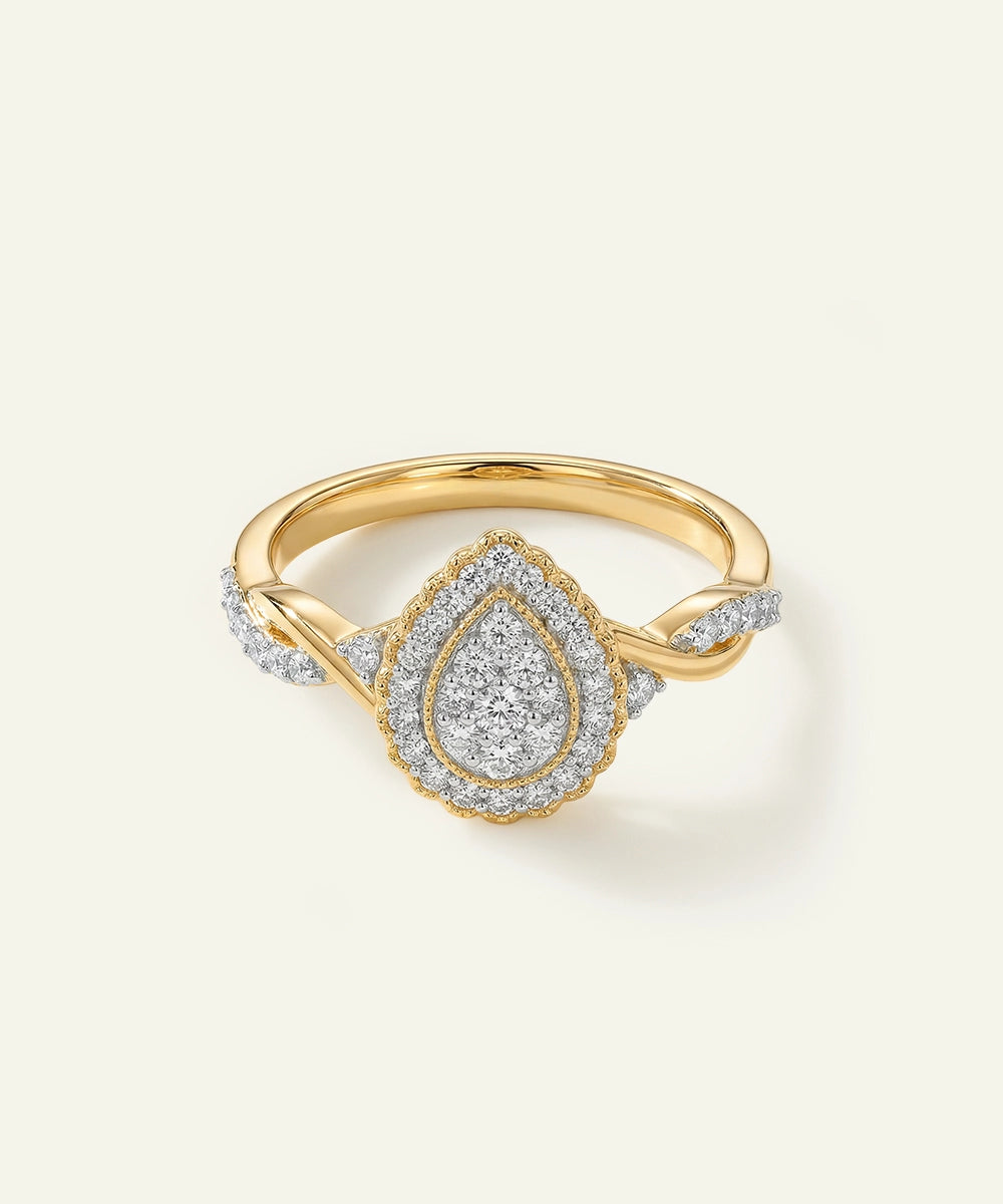 Gold ring with diamond teardrop design on a light background