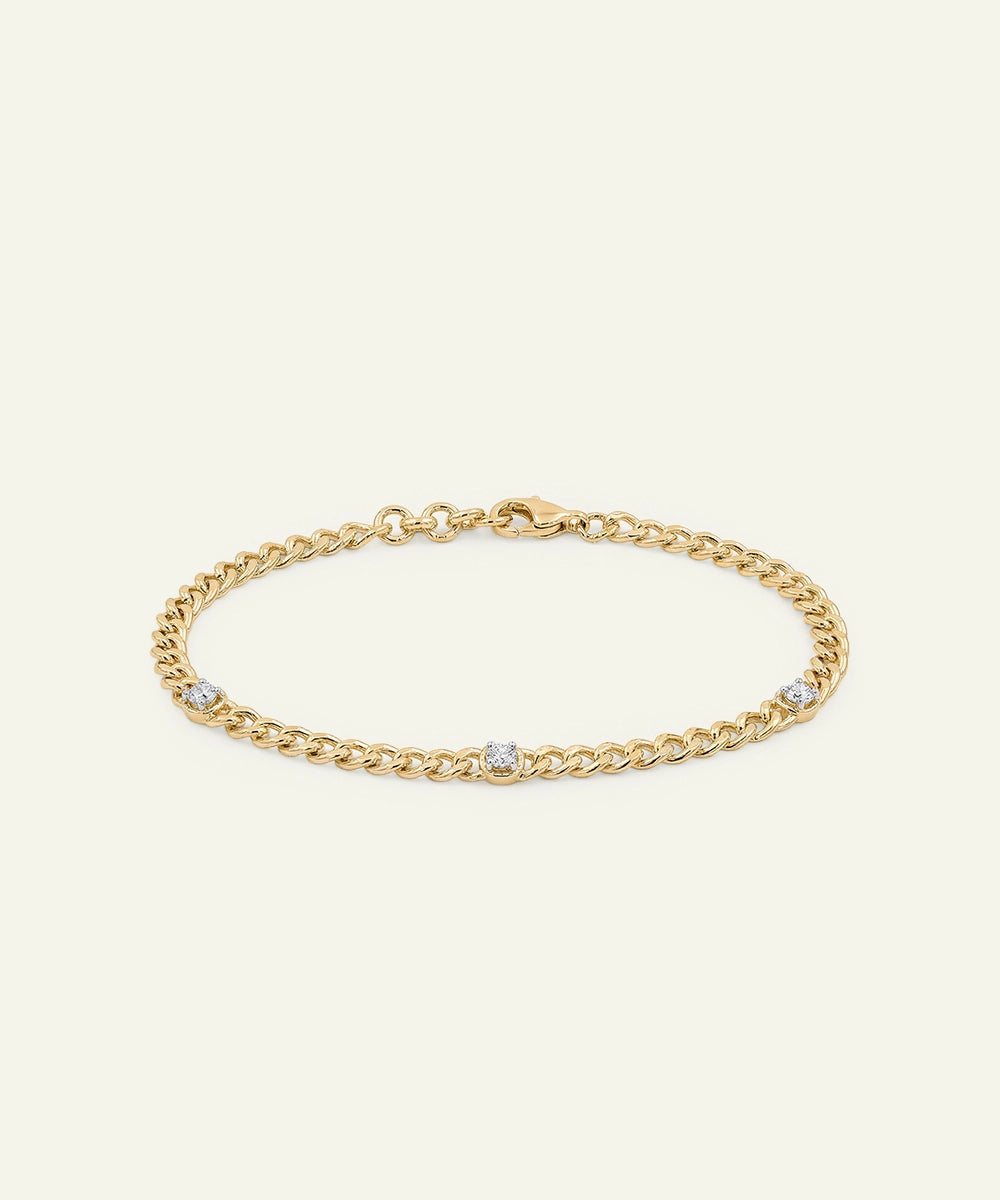 Gold chain bracelet with small diamonds on a light beige background