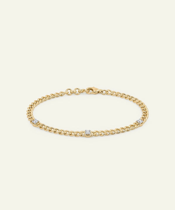 Gold chain bracelet with small diamonds on a light beige background