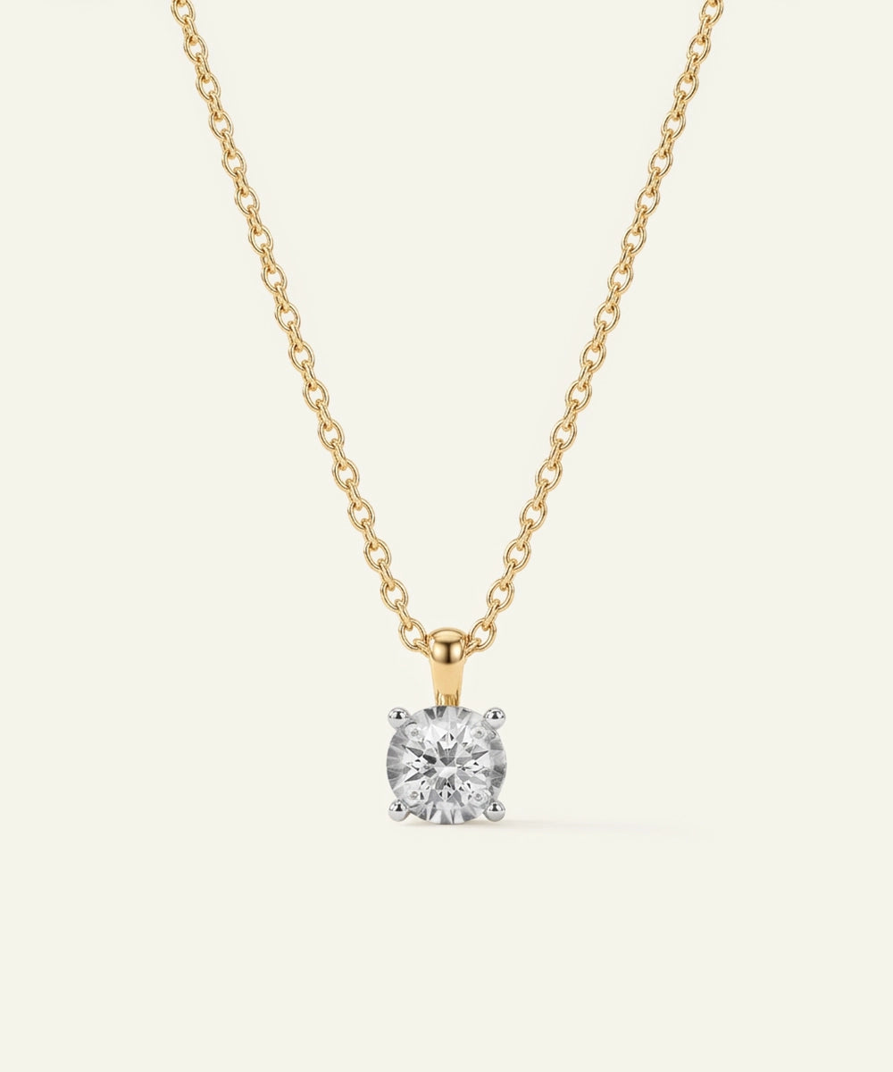 Gold necklace with a diamond pendant on a light gray background