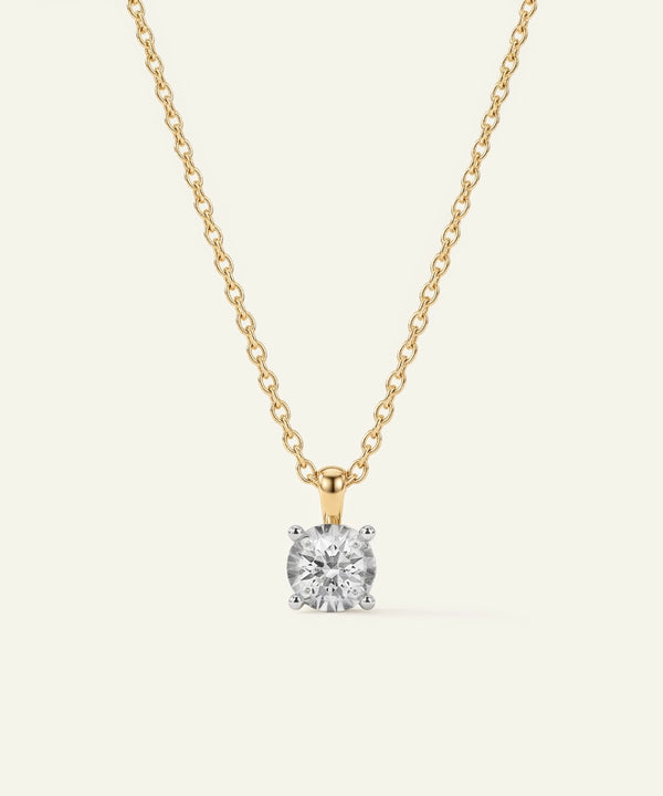 Gold necklace with a diamond pendant on a light gray background