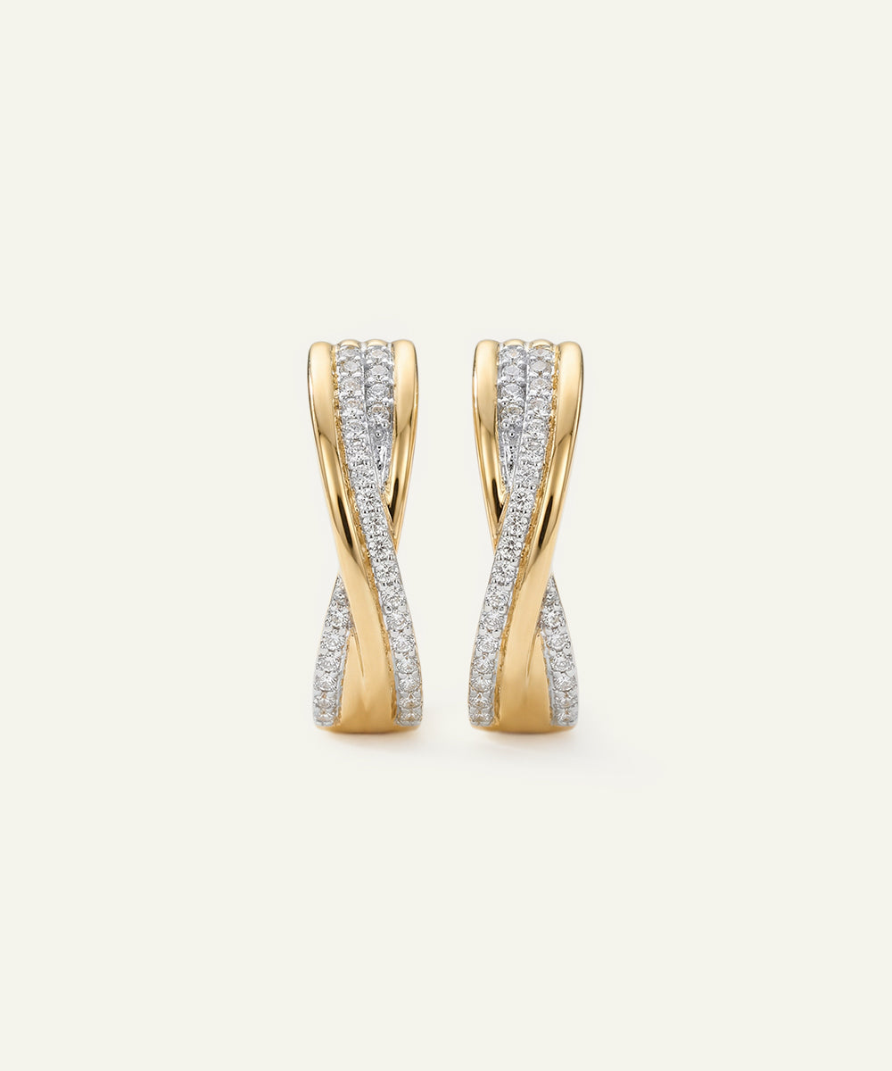 Pair of gold earrings with diamond accents on a light beige background