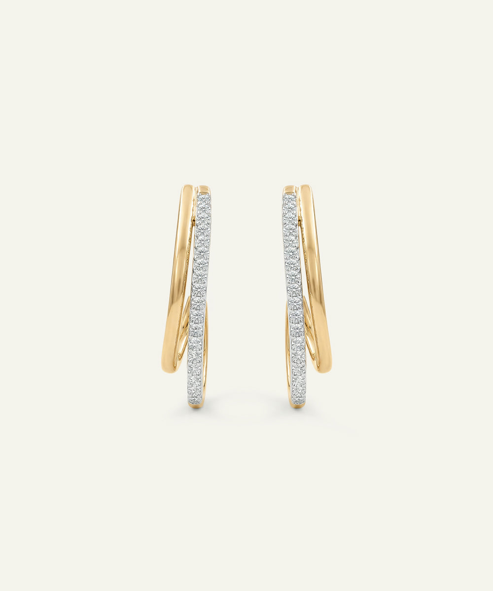 Gold hoop earrings with embedded diamonds on a light beige background