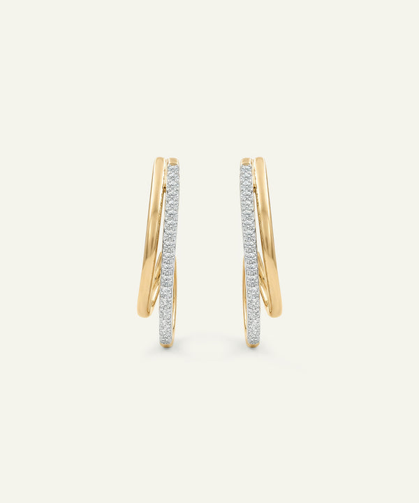 Gold hoop earrings with embedded diamonds on a light beige background