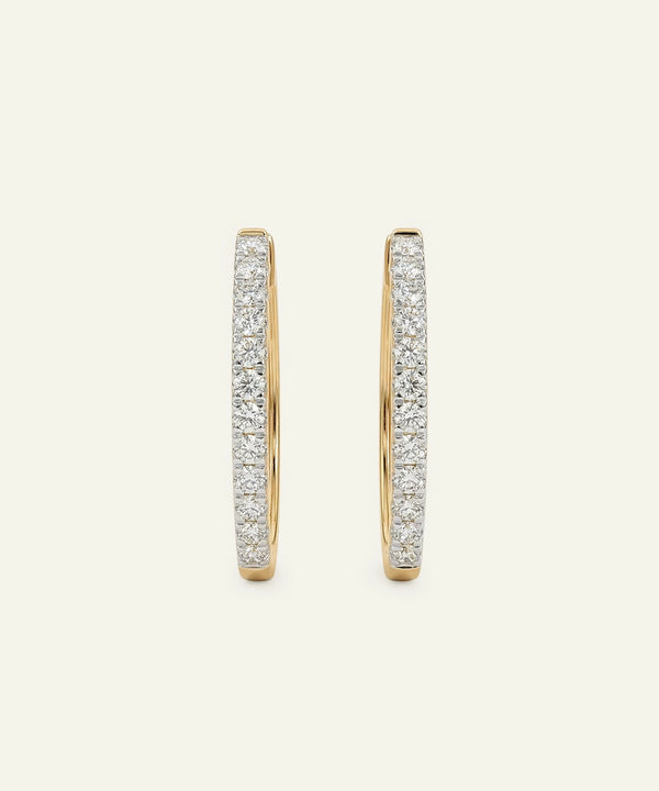 Gold hoop earrings with diamond accents on a light beige background