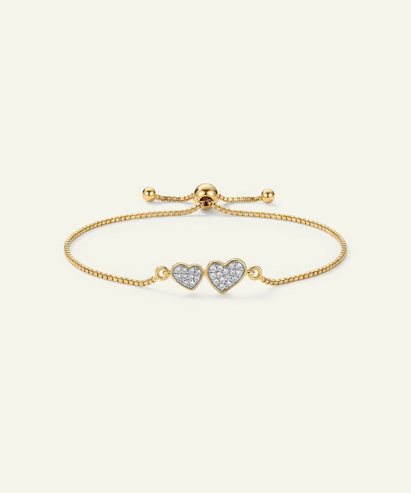 Gold bracelet with heart-shaped charms on a light beige background