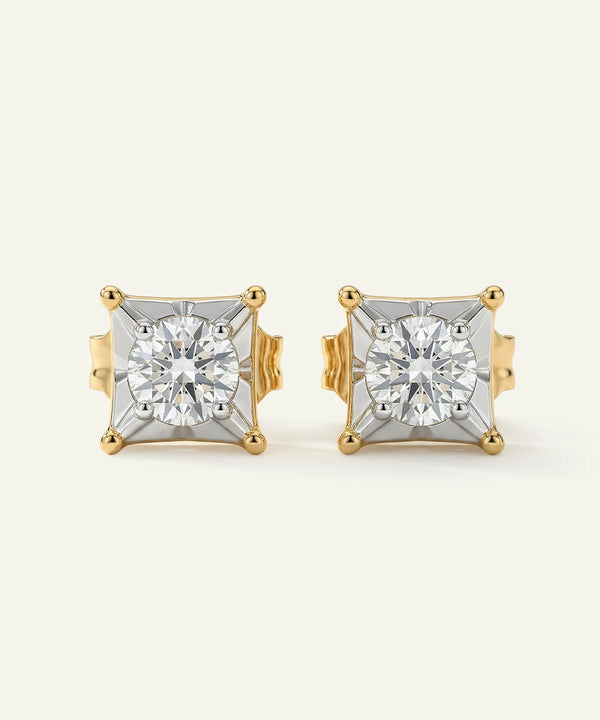Pair of gold and diamond stud earrings on a light beige background