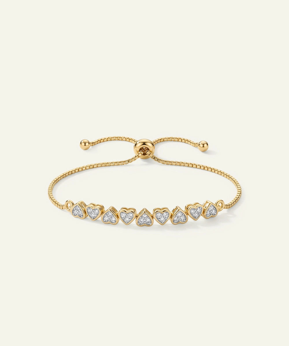 Gold bracelet with heart-shaped diamond accents on a white background