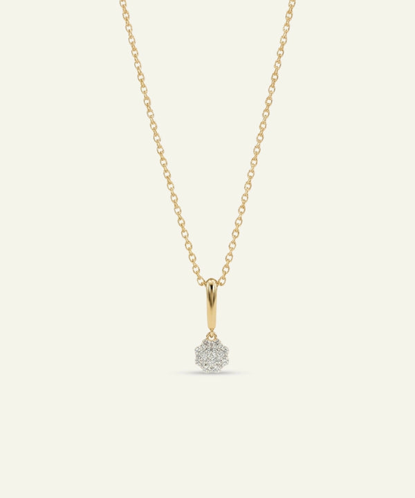 Gold necklace with a small diamond pendant on a light gray background
