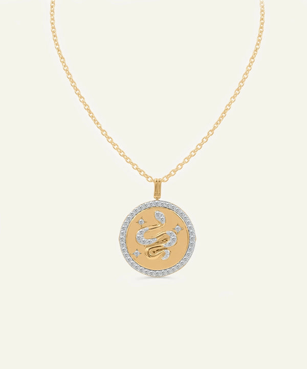 Gold necklace with a zodiac pendant on a light beige background