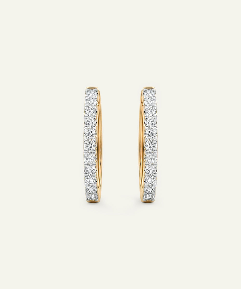 Pair of gold hoop earrings with diamond accents on a light beige background