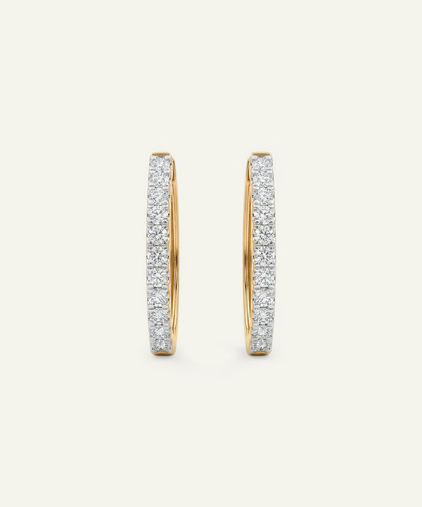 Pair of gold hoop earrings with diamond accents on a light beige background