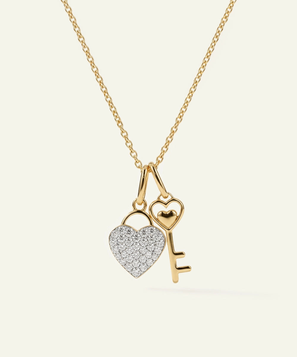 Gold necklace with heart and key pendant on a white background