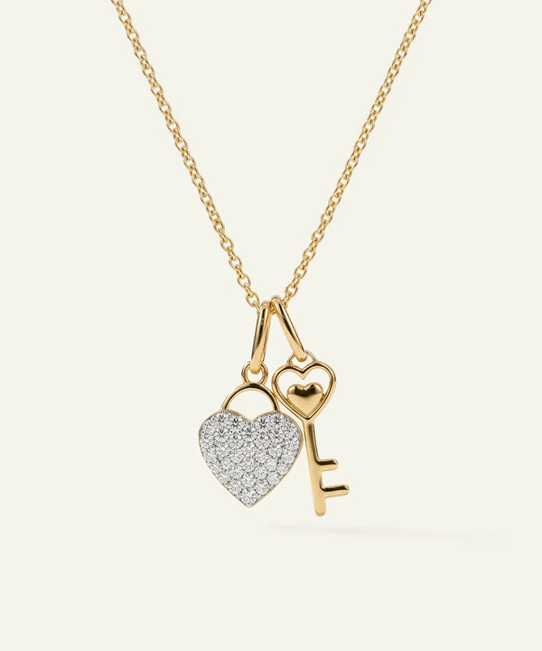 Gold necklace with heart and key pendant on a white background