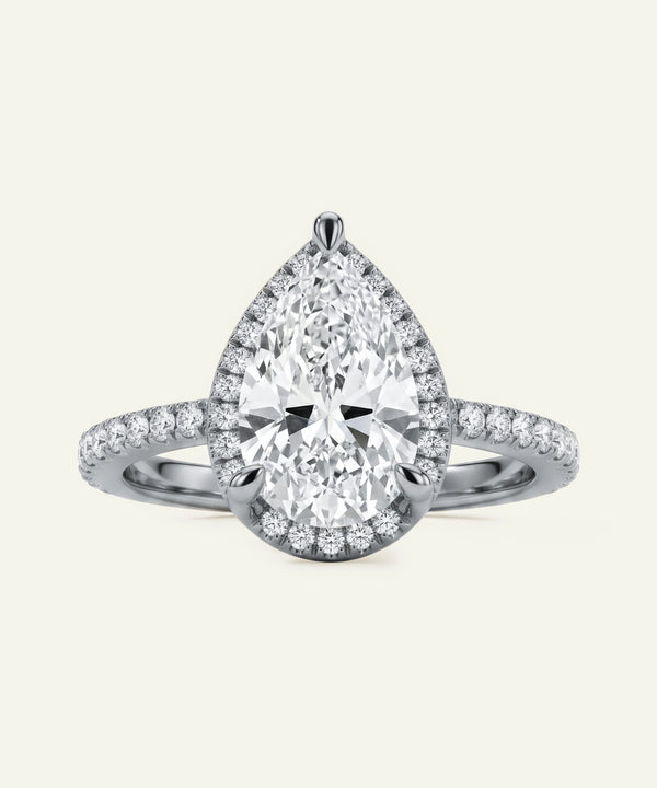 Diamond ring with pear-shaped center stone on a light gray background
