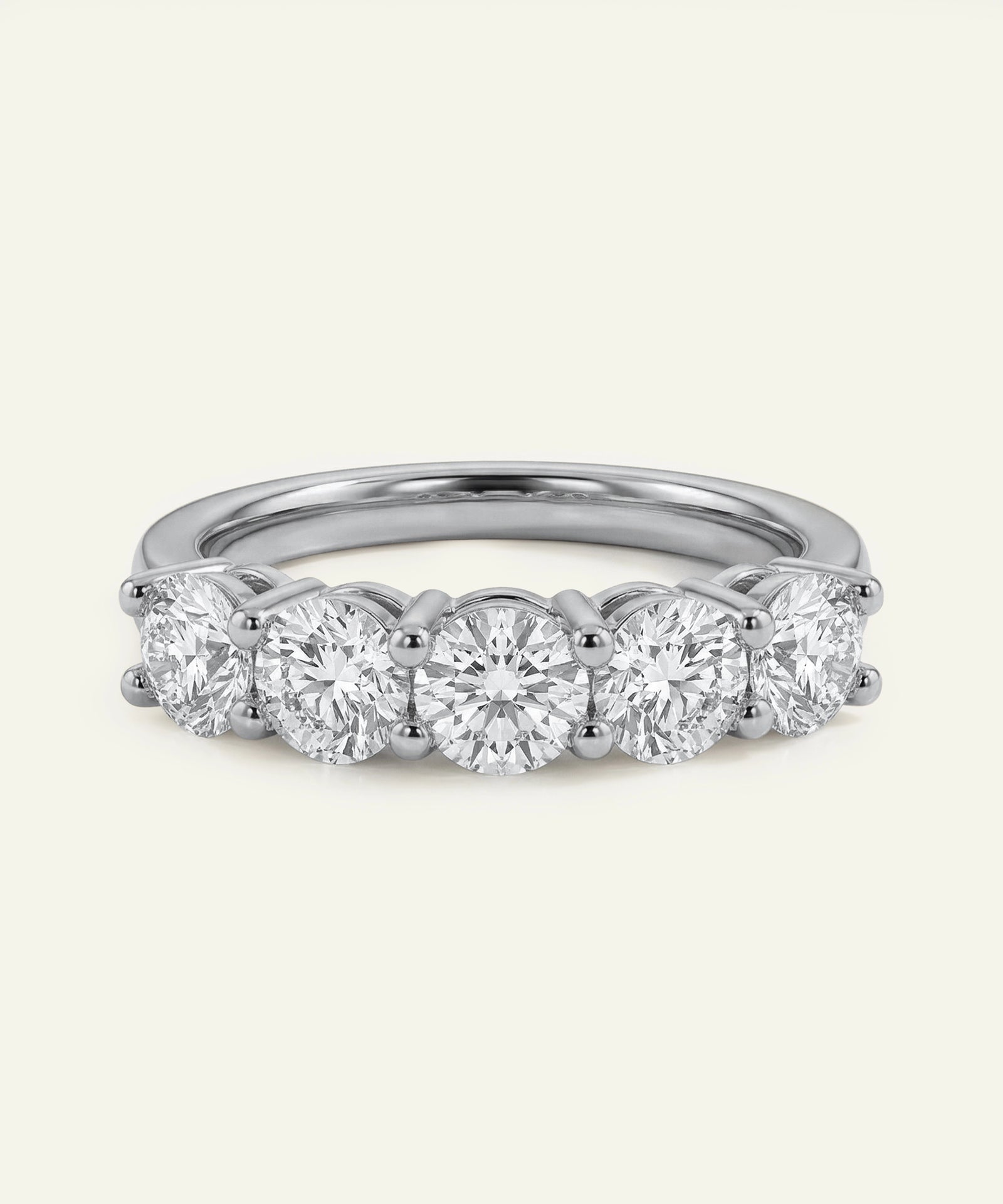 Diamond ring with five round-cut diamonds on a light gray background