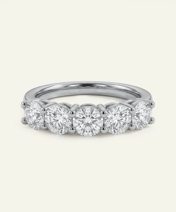 Diamond ring with five round-cut diamonds on a light gray background