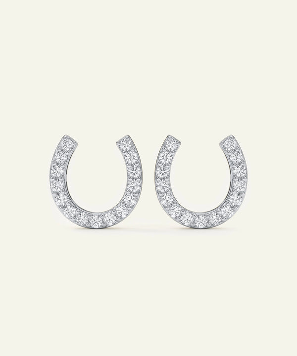 Pair of silver horseshoe-shaped earrings with clear gemstones on a white background