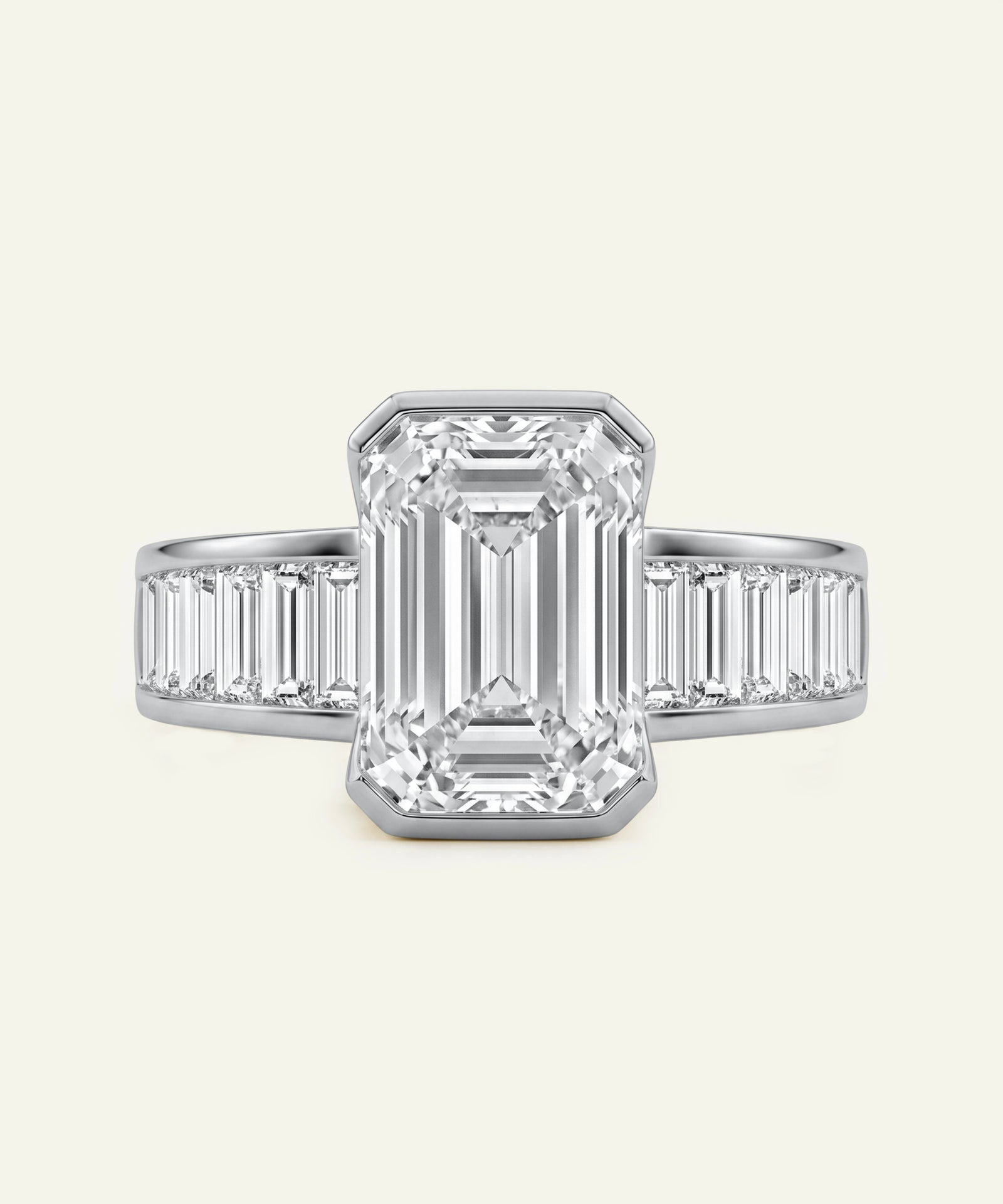 Diamond ring with emerald-cut center stone and baguette side stones on a light gray background