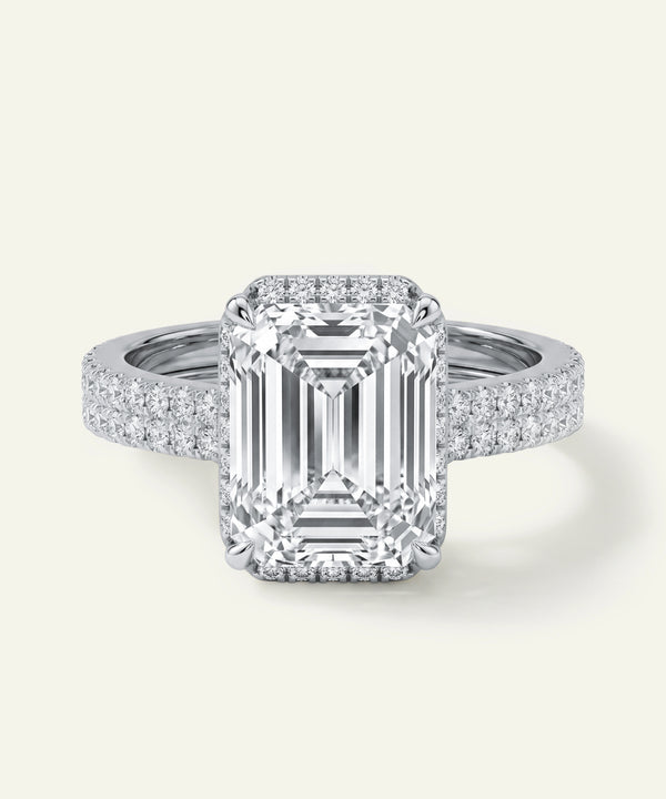 Diamond ring with emerald-cut center stone on a white background
