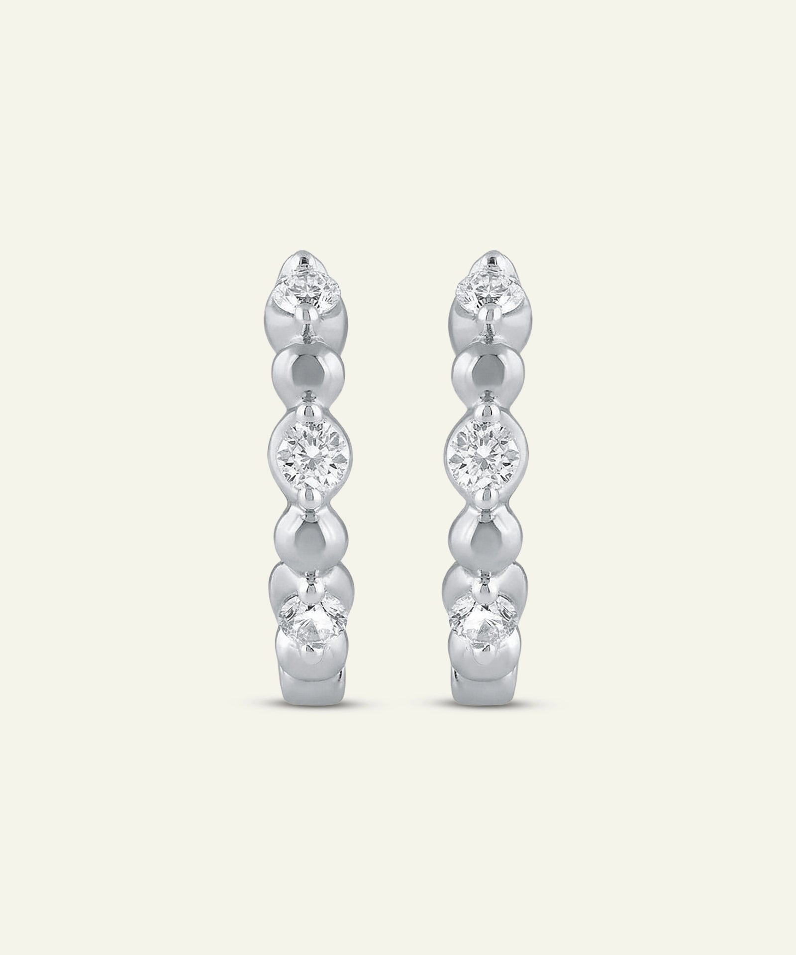 Pair of silver hoop earrings with clear gemstones on a light gray background