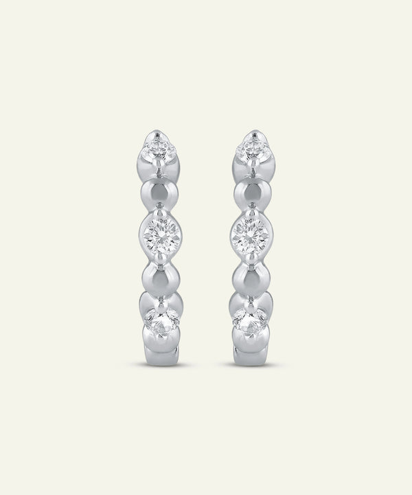 Pair of silver hoop earrings with clear gemstones on a light gray background