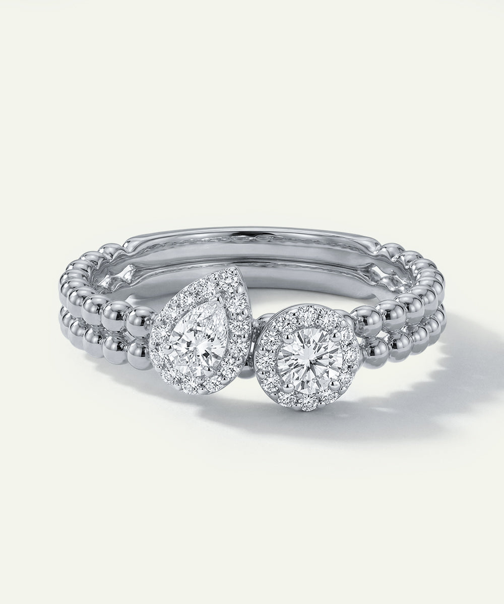 Diamond ring with pear-shaped and round stones on a white background