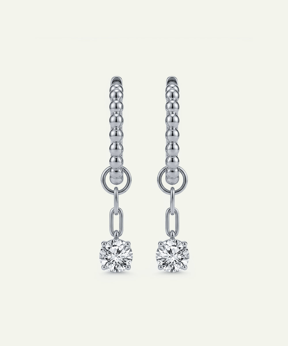 Silver earrings with diamond drops on a light gray background