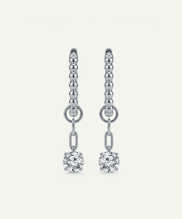 Silver earrings with diamond drops on a light gray background