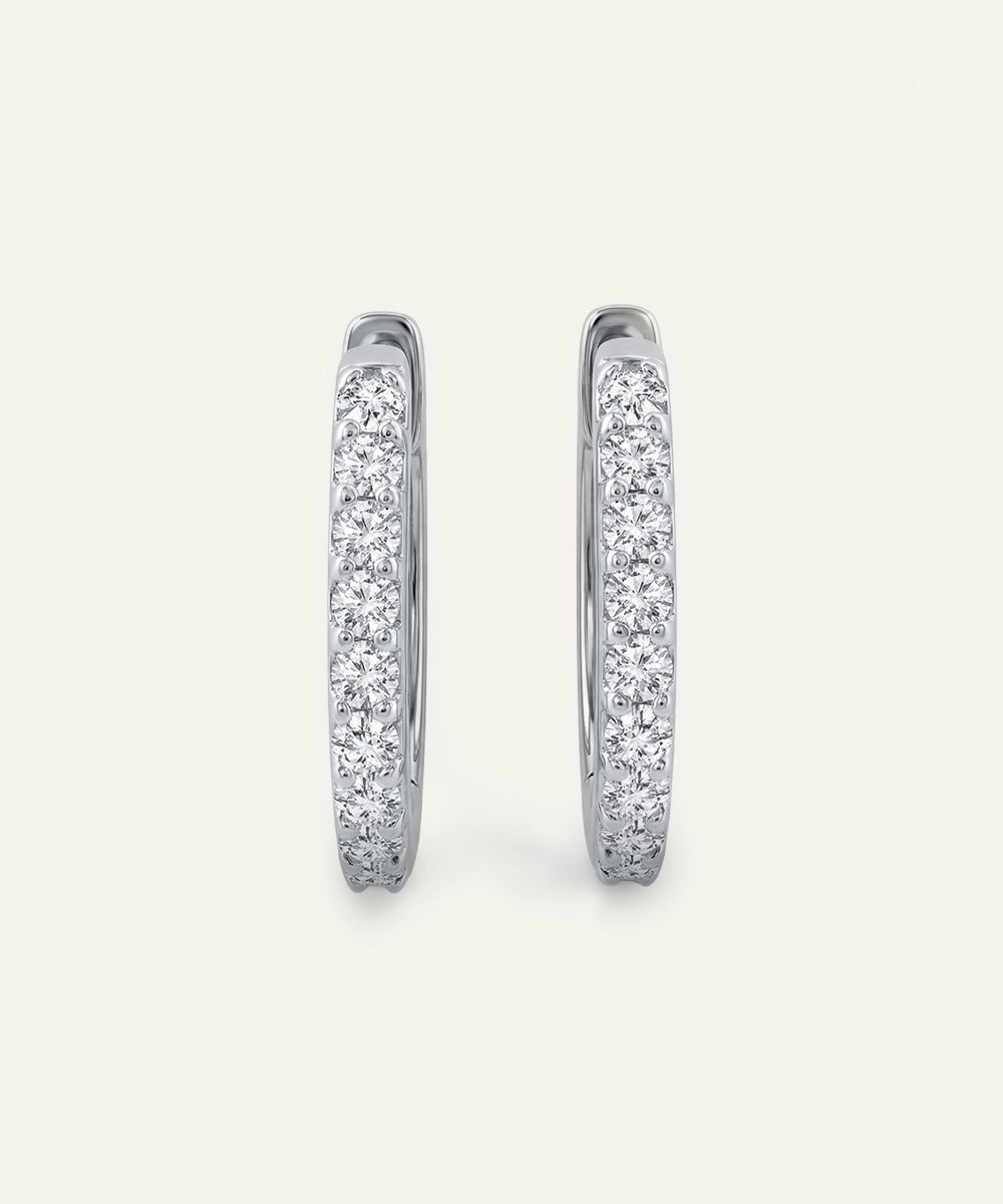 Pair of silver hoop earrings with embedded stones on a light gray background