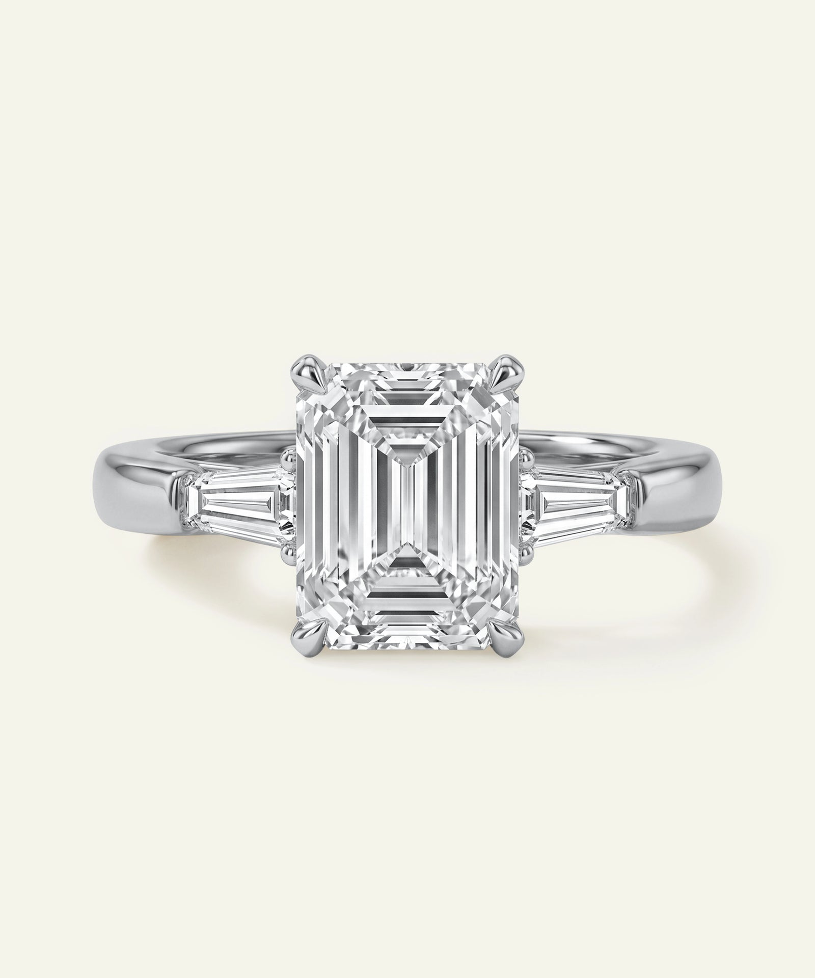 Diamond ring with emerald-cut center stone on a white background