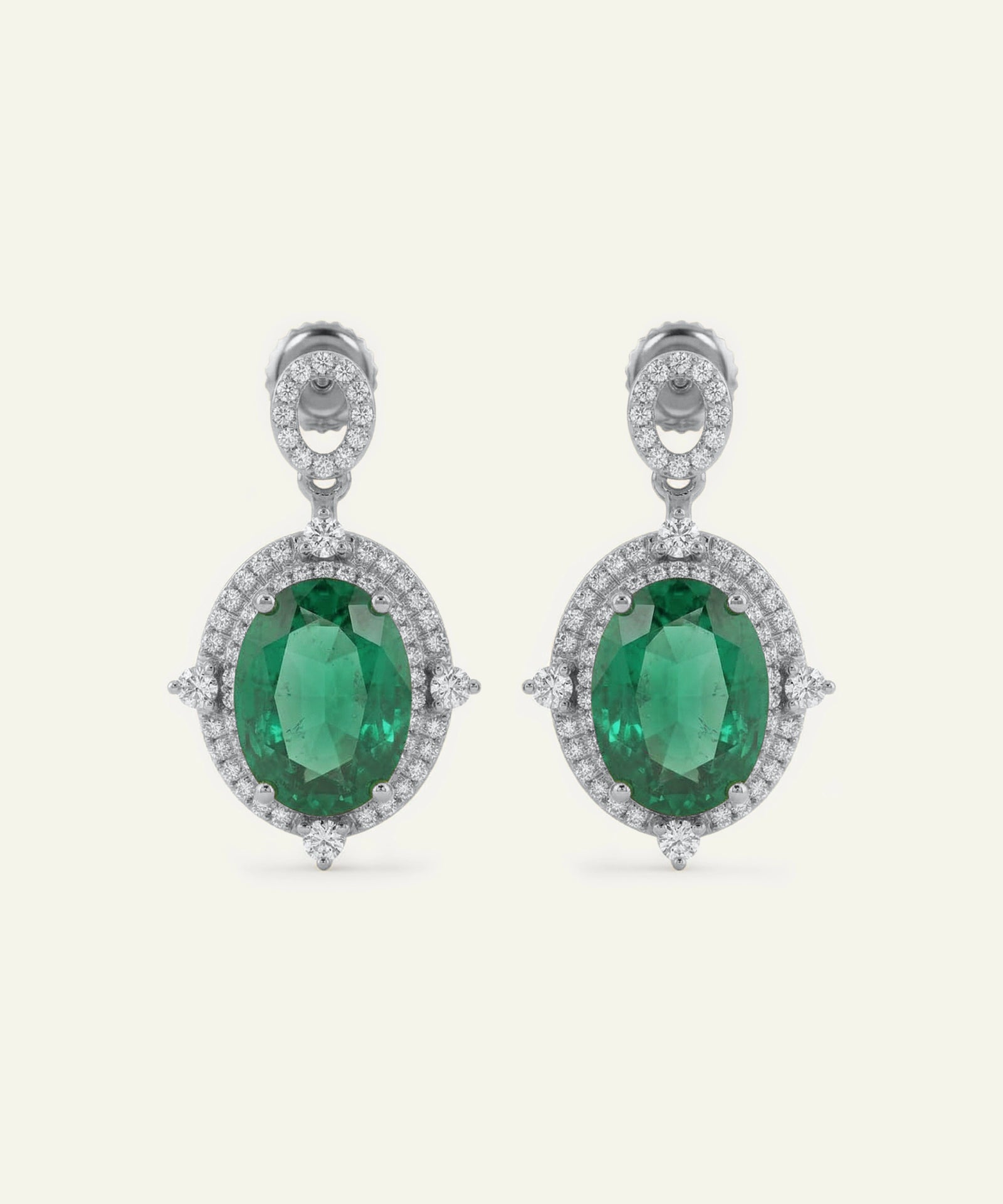 Pair of emerald earrings with diamond accents on a white background