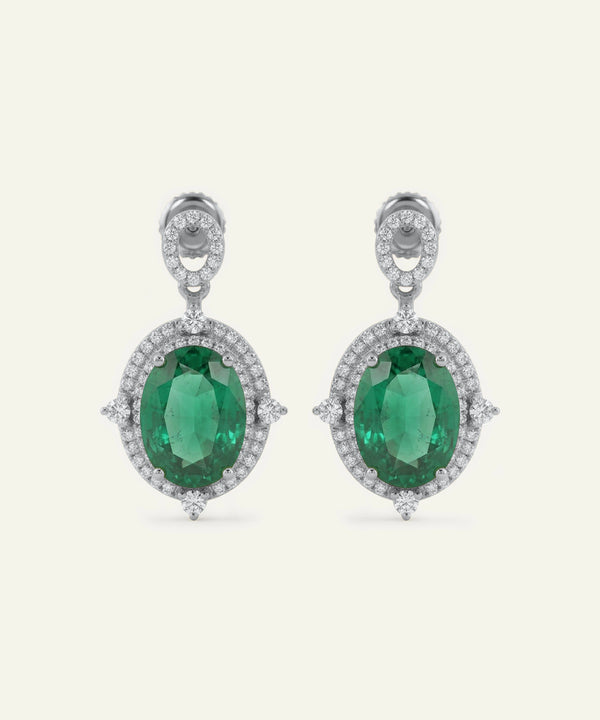 Pair of emerald earrings with diamond accents on a white background