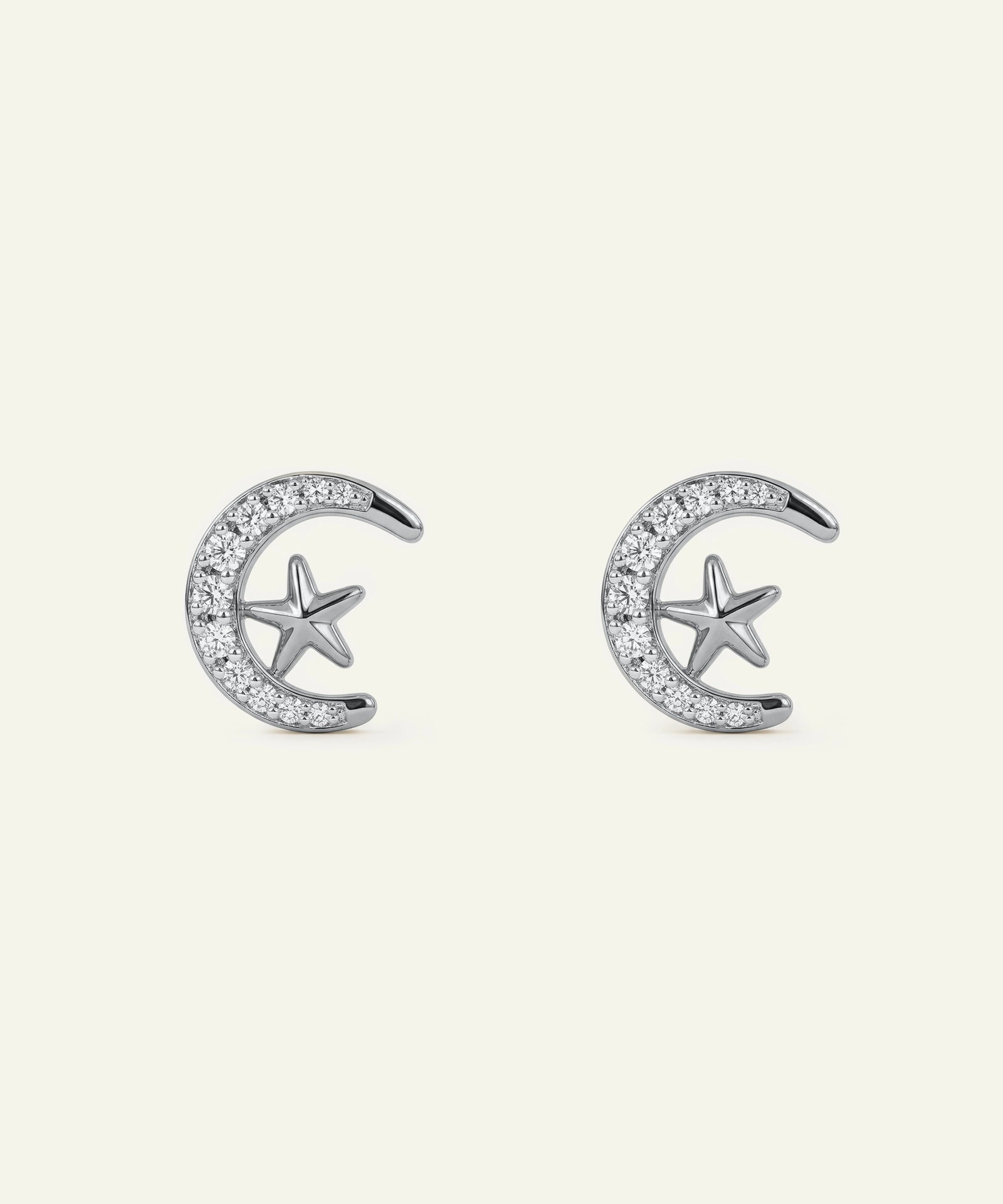 Silver earrings with star and crescent moon designs on a white background