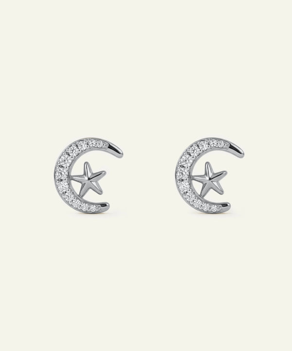 Silver earrings with star and crescent moon designs on a white background
